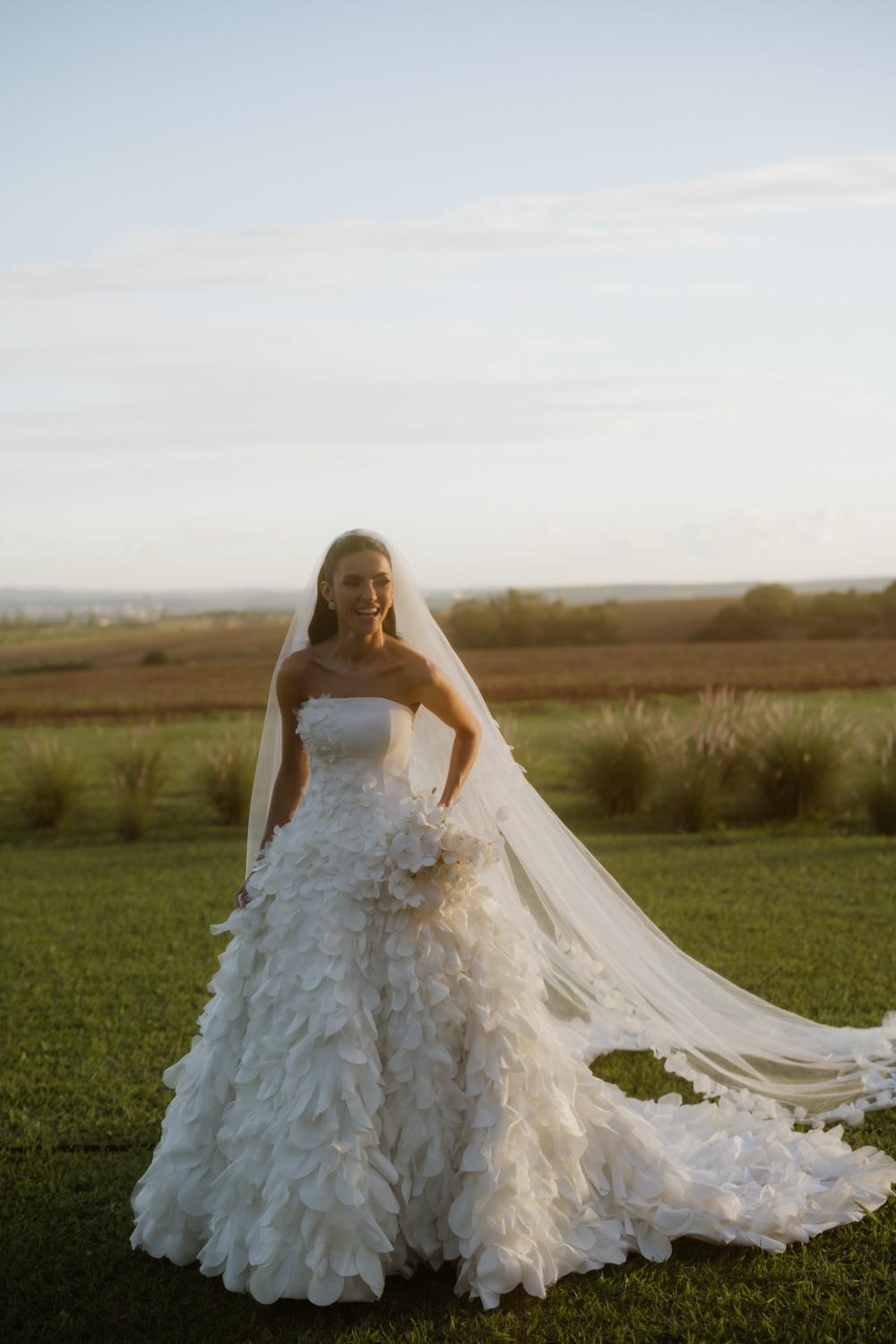 Bride smiling in the field with a long veil
